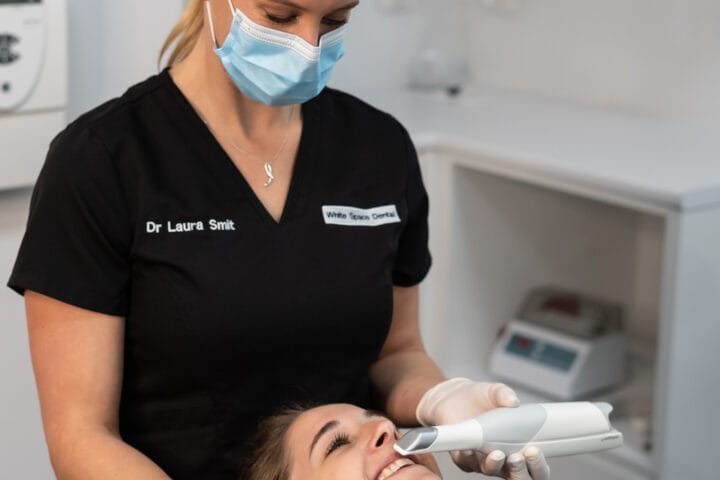 Dr. Laura Smit uses an intraoral scanner on a smiling patient during a consultation to get her teeth whitened at the dentist.